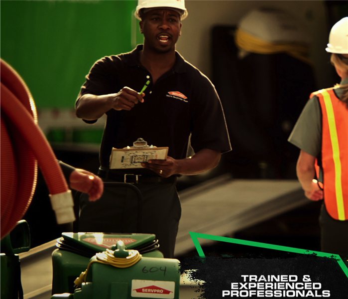 SERVPRO crew wearing protective head gear standing in front of equipment with caption: TRAINED & EXPERIENCED PROFESSIONALS